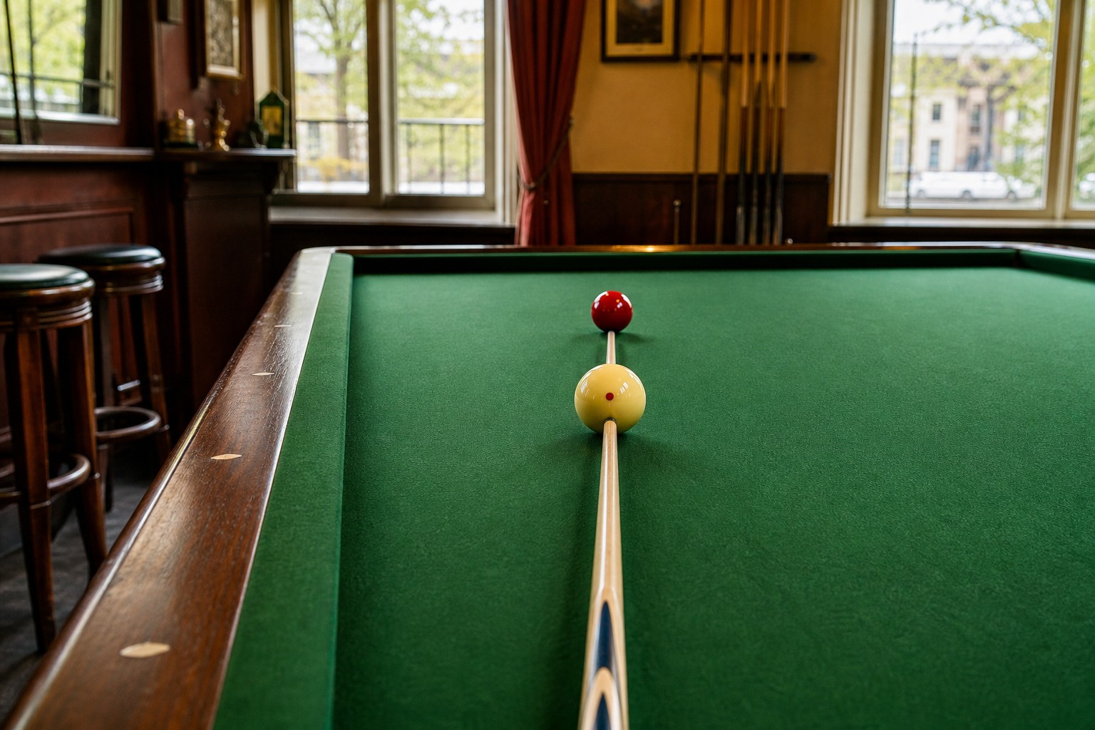 Biljartkeu ligt recht achter een witte bal op een groen biljartlaken